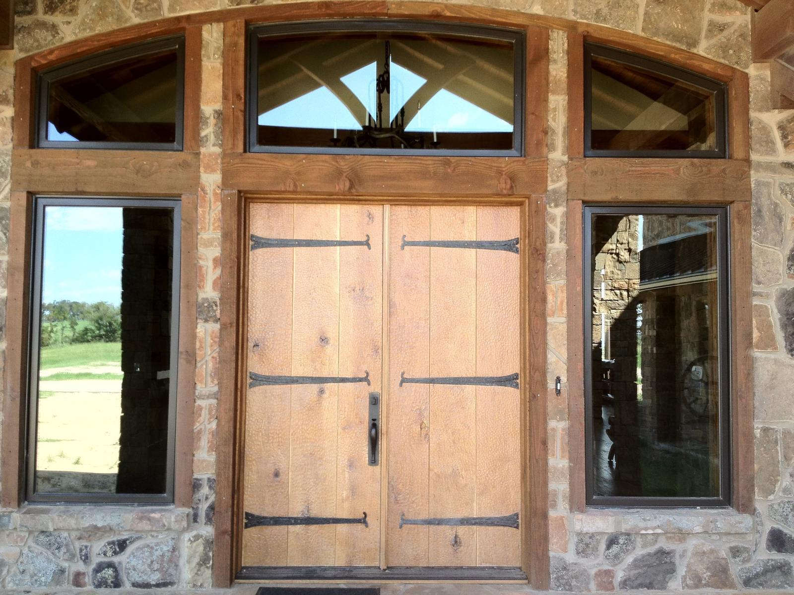 Installed pair of plank wood doors beneath arched windows
